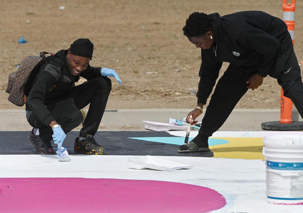 De’Marion “D’mac” Hackett, left, and Leo Hodge, right, help paint a giant mural with other volunteers along Klette Avenue just north of California Ave. as part of the West Fresno California Avenue Neighborhood (CAN) initiative Saturday, May 6, 2023 in Fresno. Area residents and artists gatherd to paint the permanent mural as part of a revitalization effort.