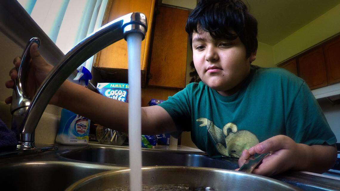 Nine-year-old Jose Hernandez draws tap water in his Earlimart home for dishwashing, one of the few purposes his family uses well water for due to lingering fears of contamination of the ground water. Earlimart is an unincorporated community in Tulare County.