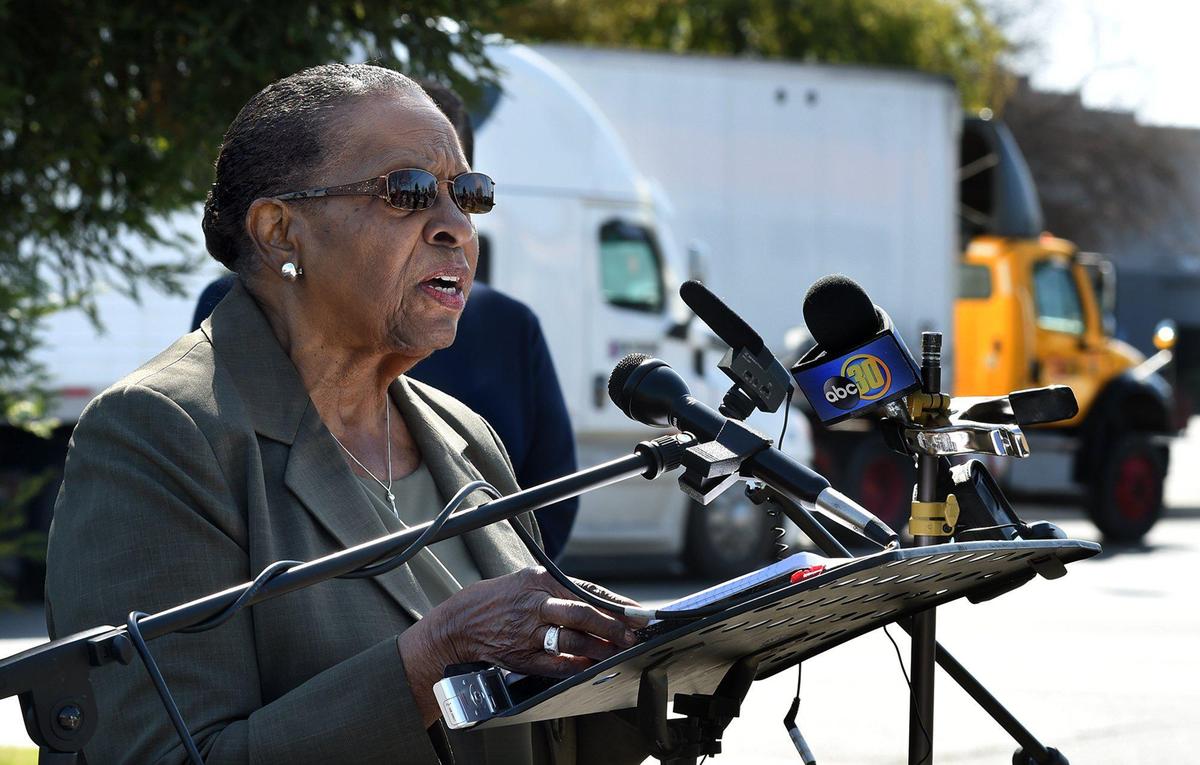 A pair of semi-trucks roll by on Elm Avenue, as Mary Curry, longtime community activist and member of Concerned Citizens of West Fresno, speaks during a press conference, March 26, 2021, to voice opposition against the proposed Elm Avenue rezone that goes before the planning commission next month, and the health impacts it will have on the community, due to increase pollution.