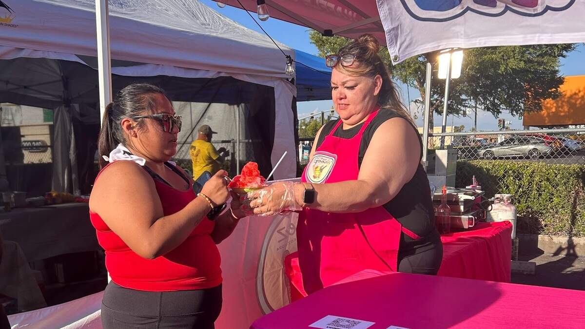 Christela Espinoza, left, hands shaved ice to a customer at the Lanz Ohana Market on June 12.