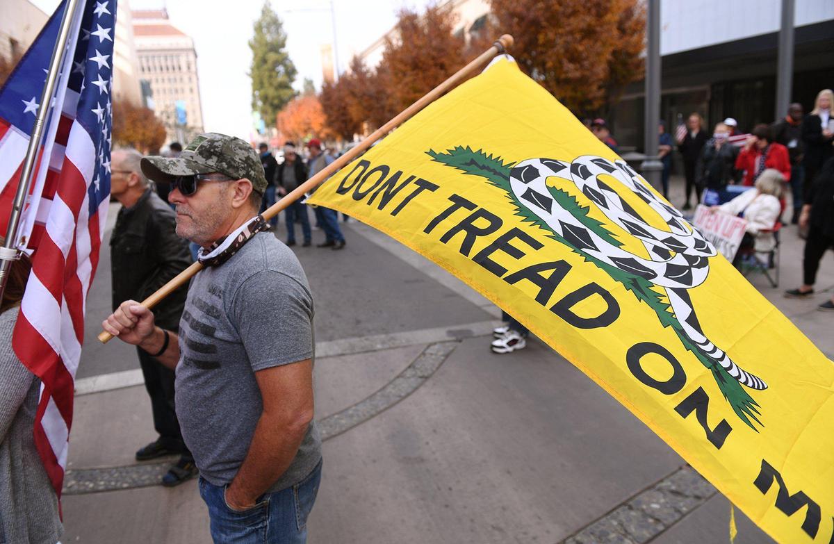 A man holds a Don’t Tread On Me flag as at least 200 people gather on Fulton Street in front of the Fresno County Department of Public Health to protest California and Gov. Gavin Newsom’s purple-tier restrictions on restaurants during a rally Saturday, Nov. 21, 2020, in downtown Fresno.