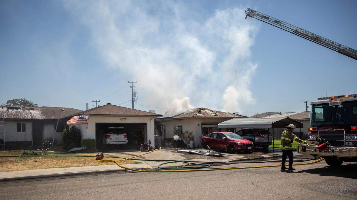 Firefighters extinguish a fire that destroyed two homes in Clovis on Friday, July 31, 2020.