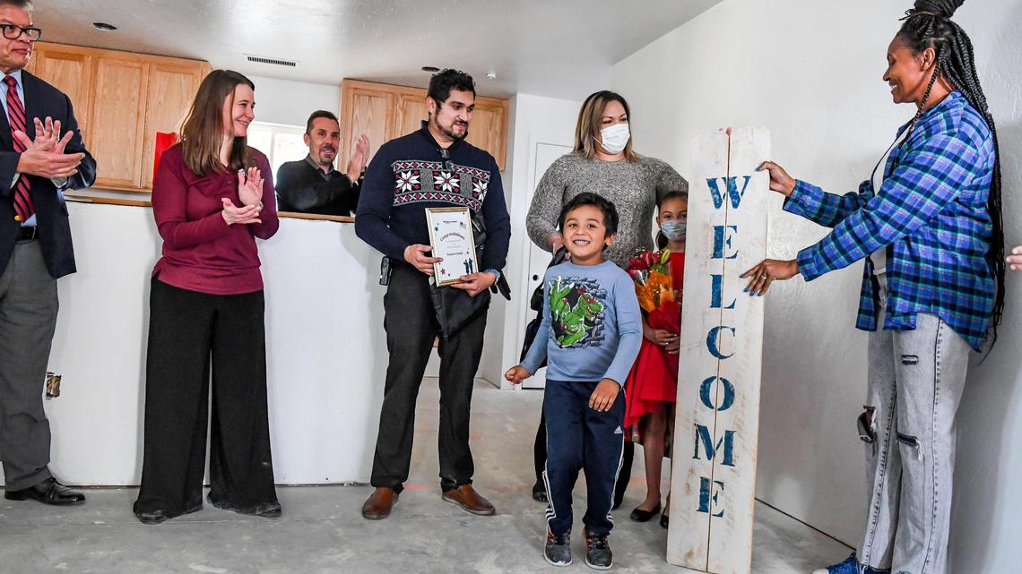 Members of the Delgado family are presented with a welcome sign by neighbor Chelsea Allen after being announced as the recipients of the newest Habitat for Humanity build in Clovis on Wednesday, Dec. 8, 2021.