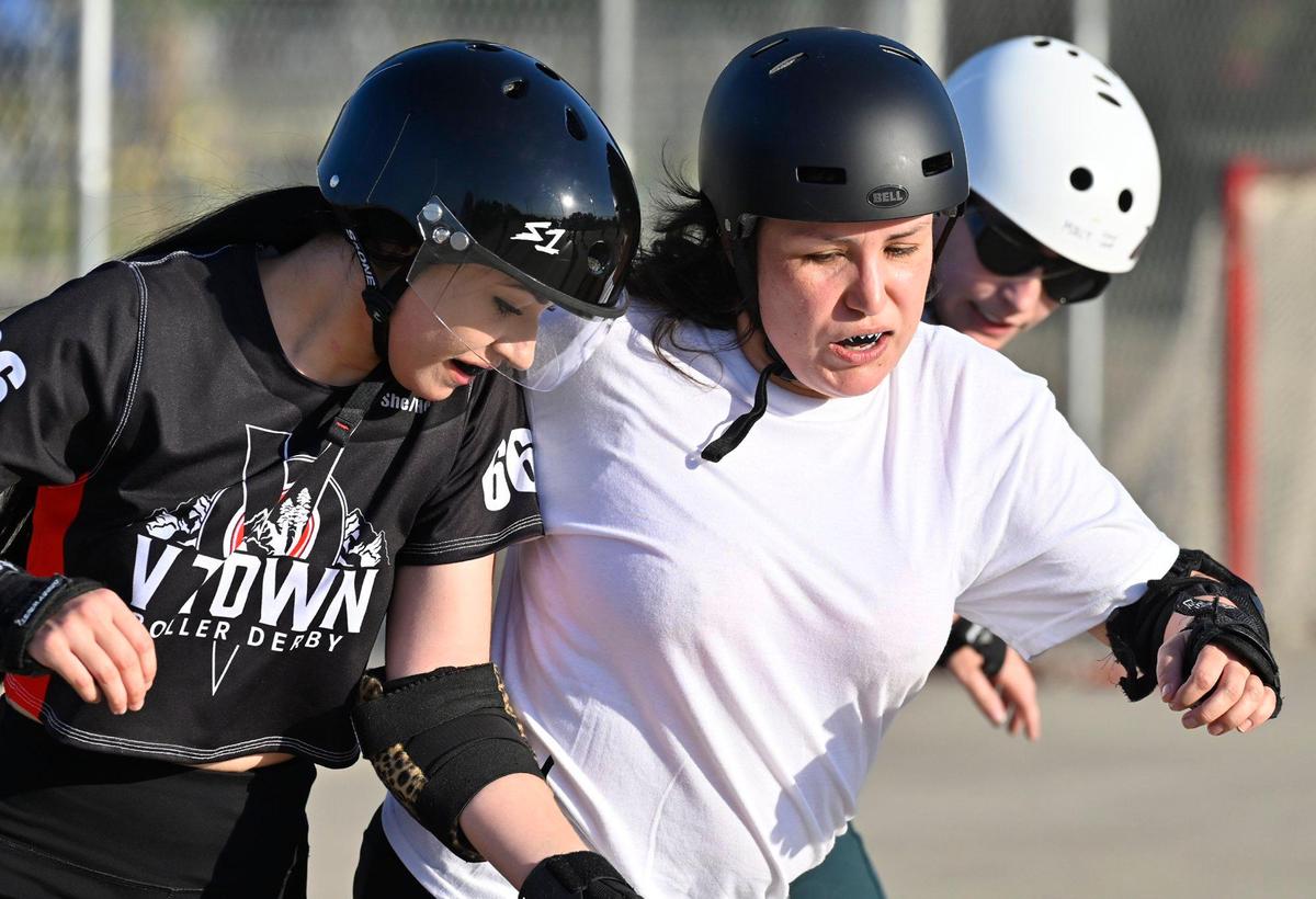 Maria “Kourt-knee Kar-Bash-U-In” Lewis, center, breaks through Haley Woolhouse, left, and Emily “Molly Hatchet” Artz, right, at the Ash City Roller Derby practices a Cary Park on Thursday, May 6, 2025, in Fresno, California.