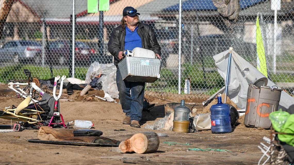 Chris North carries a box of some of his belongings as he departs a homeless encampment while Fresno’s Homeless Assistance Response Team (HART) begins a homeless camp cleanup operation behind several shelters on Parkway Drive in Fresno on Wednesday, Feb. 1, 2023