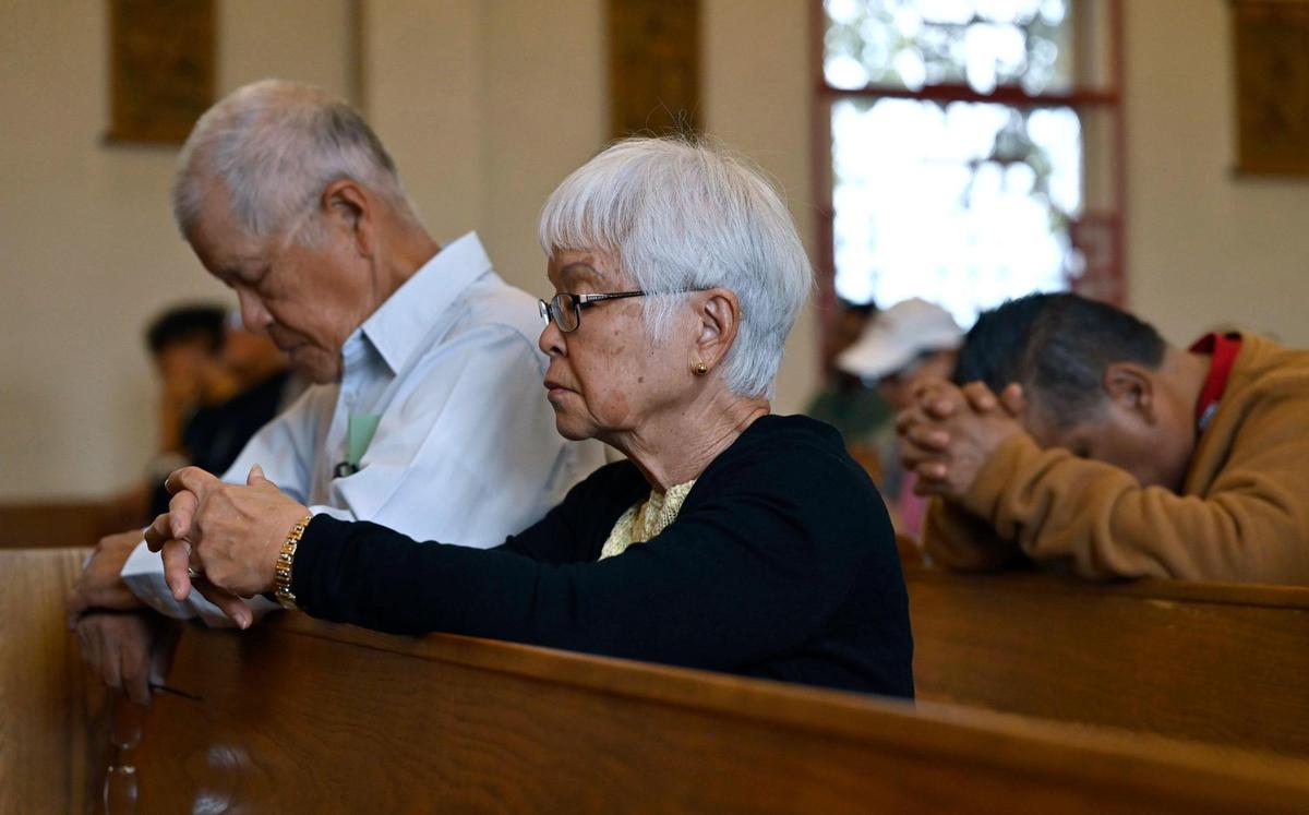 Edwin Lee, left, and his wife Rena Lee, center, pray during Mass at St. Genevieve Catholic Church in Chinatown, Sunday, Oct. 27, 2024, in Fresno.