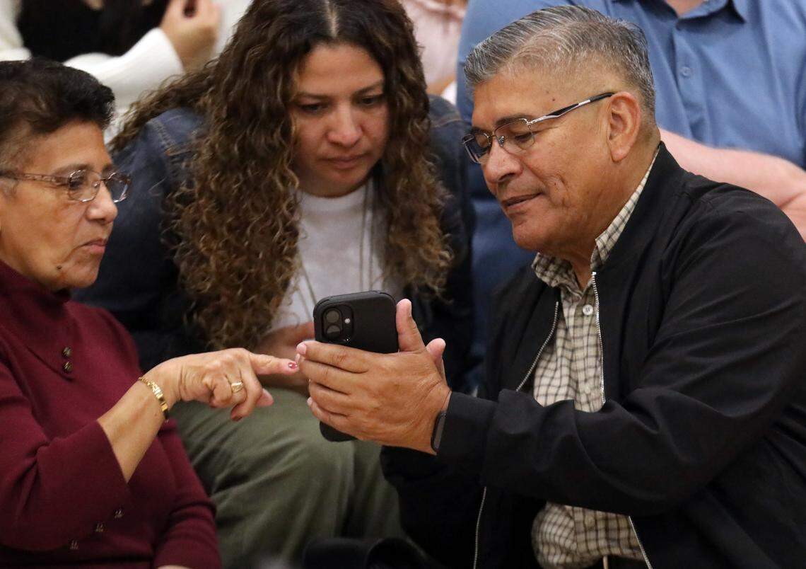 A family looks at cell phone photos they took at the 23rd annual Latino Achievement Graduation at the Fresno City College Gym on May 17, 2025.