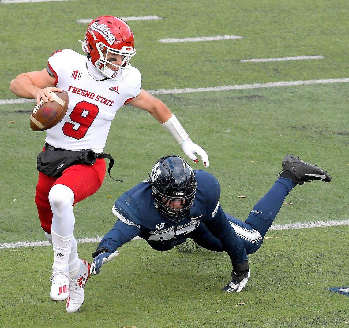 Fresno State quarterback Jake Haener (9) scrambles away from Utah State defensive lineman Jake Pitcher (97) during the first half of an NCAA college football game, Saturday, Nov. 14, 2020, in Logan, Utah. (Eli Lucero/Herald Journal via AP)