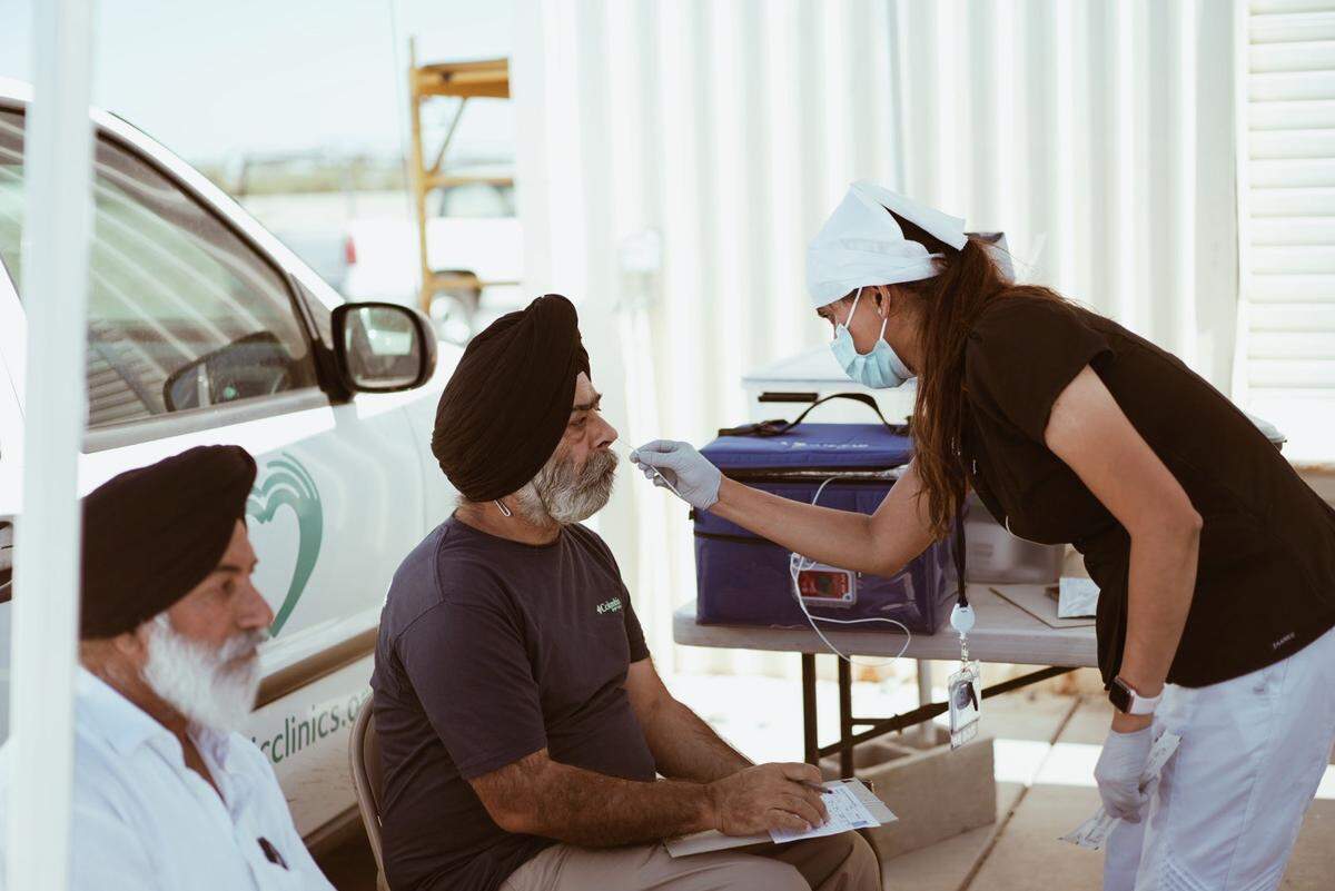A community health worker with the Jakara Movement performs a COVID test at a free clinic set up at a Sikh temple in the City of Tracy in July, 2022.