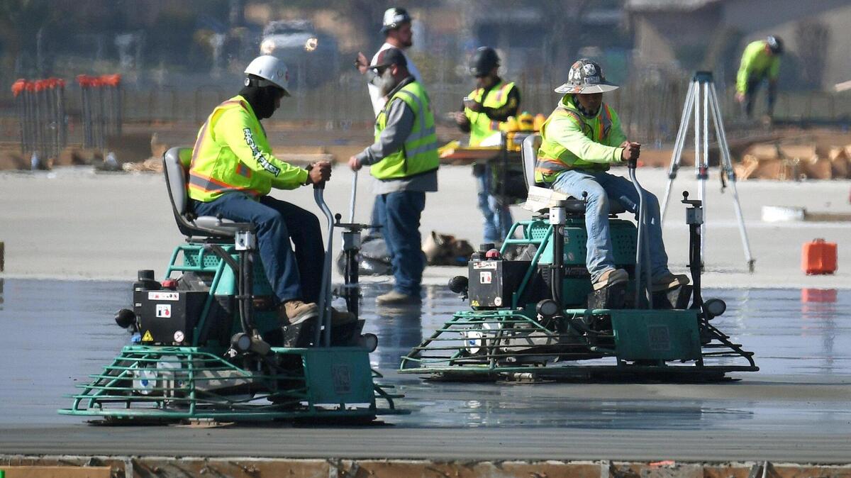 Trabajadores usan máquinas para alisar la superficie de un cimiento de concreto para un nuevo almacén de Amazon en el este de Fresno, el 9 de febrero de 2022. El terreno rodea el antiguo Sunnyside Drive-In en las avenidas Olive y Clovis.