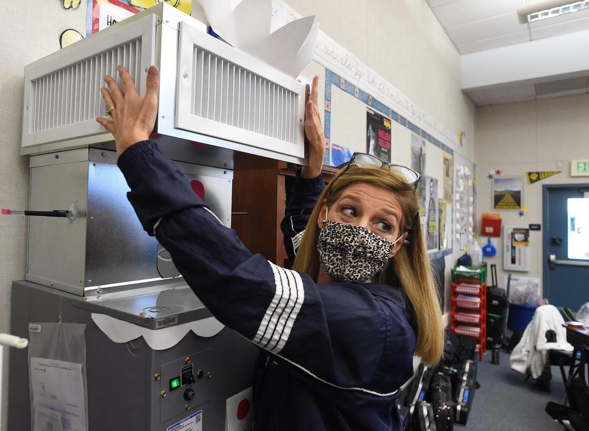 Clovis Elementary School fifth grade teacher Tina Volanti feels the gentle output of air of the HEPA-grade Carrier air filtration unit in her class. The system is installed in nearly every indoor space in Clovis Unified.
