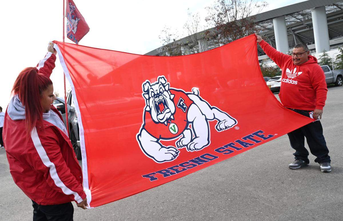 Cecilia Perez, left, holds a huge Fresno State Bulldogs banner with her father Robert Perez to the right as the Red Wave arrives at SoFi Stadium for the Jimmy Kimmel LA Bowl against Washington State Saturday, Dec. 17, 2022 in Inglewood.