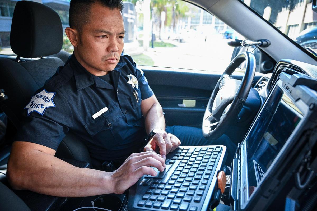 Fresno police department public information officer Luke Tran logs into his vehicle computer system in his patrol car near police headquarters on Mariposa Mall in downtown Fresno photographed on Monday, Feb. 10. 2025. The department began using artificial intelligence to write some of their reports over the past year.