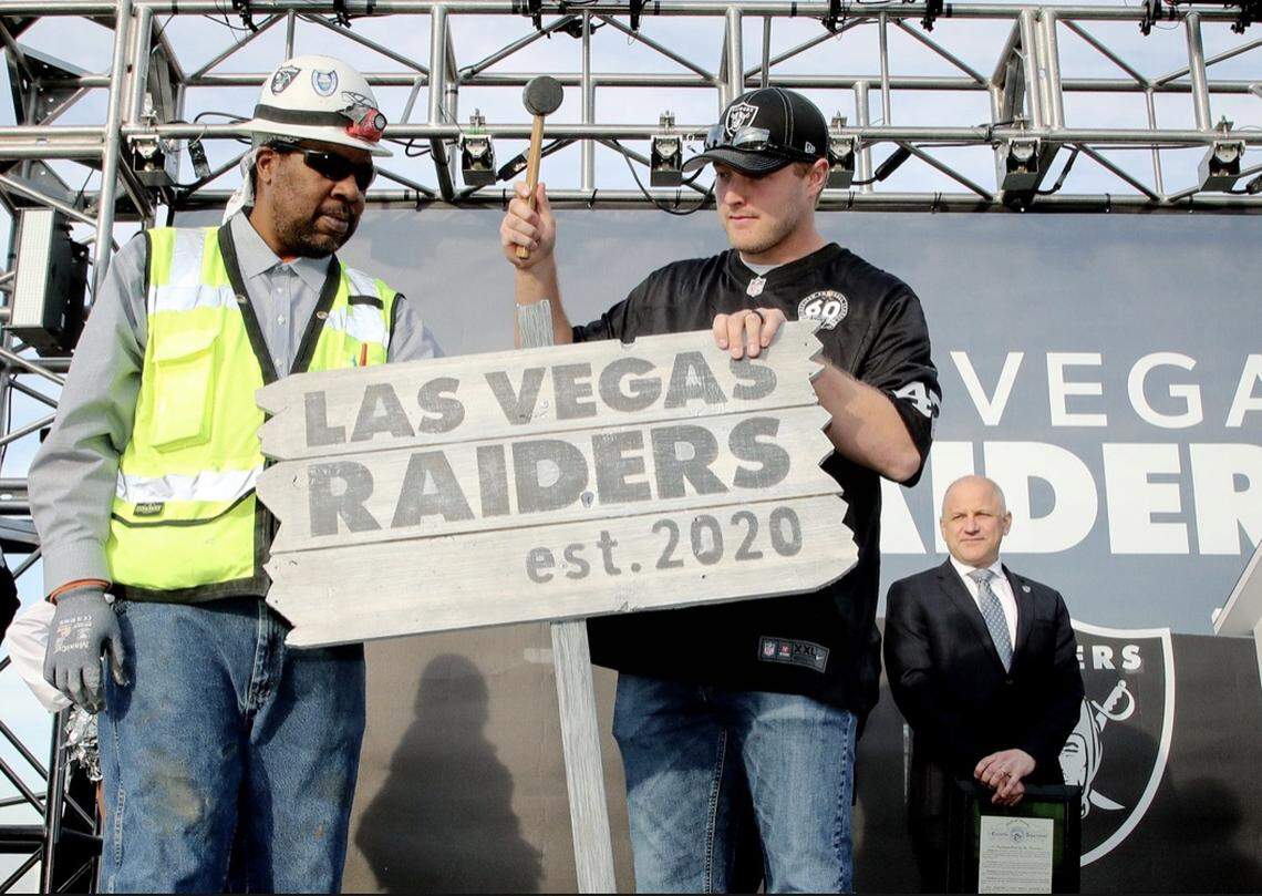 Las Vegas Raiders long snapper Trent Sieg helps a construction worker at the team unveiling at Allegiant Stadium in January.