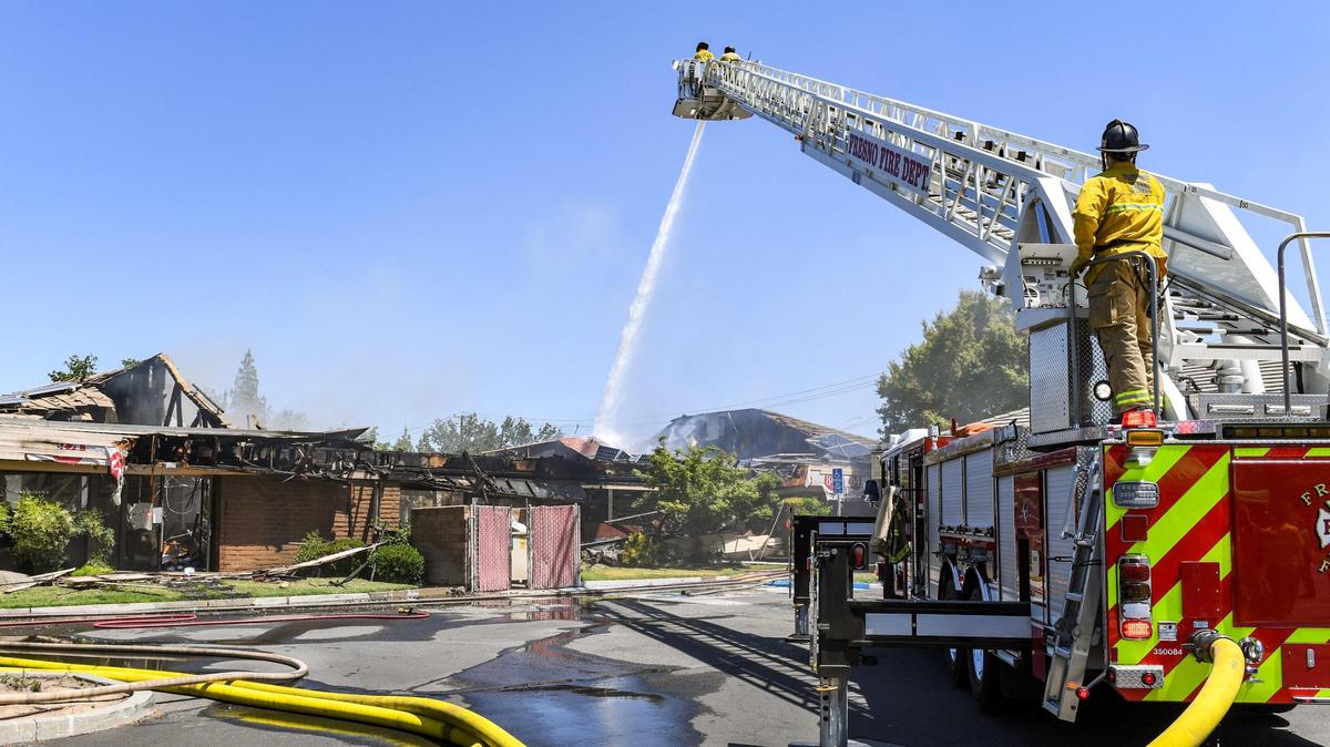 Firefighters on a Fresno Fire Department ladder truck put water on a fire burning in a commercial building at First Street and Bullard Avenue on Fresno on Friday, May 7, 2021.