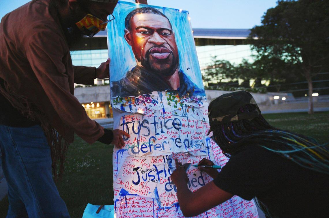 Monique McNeal, right, adds 16-year old Ma’Khia Bryant’s name to the list of those killed by police following a solemn gathering in front of Fresno City Hall, marking the guilty verdict for former police officer Derek Chauvin in the death of George Flloyd earlier in the day. Photographed at a rally Tuesday evening, April 20, 2021 in Fresno.