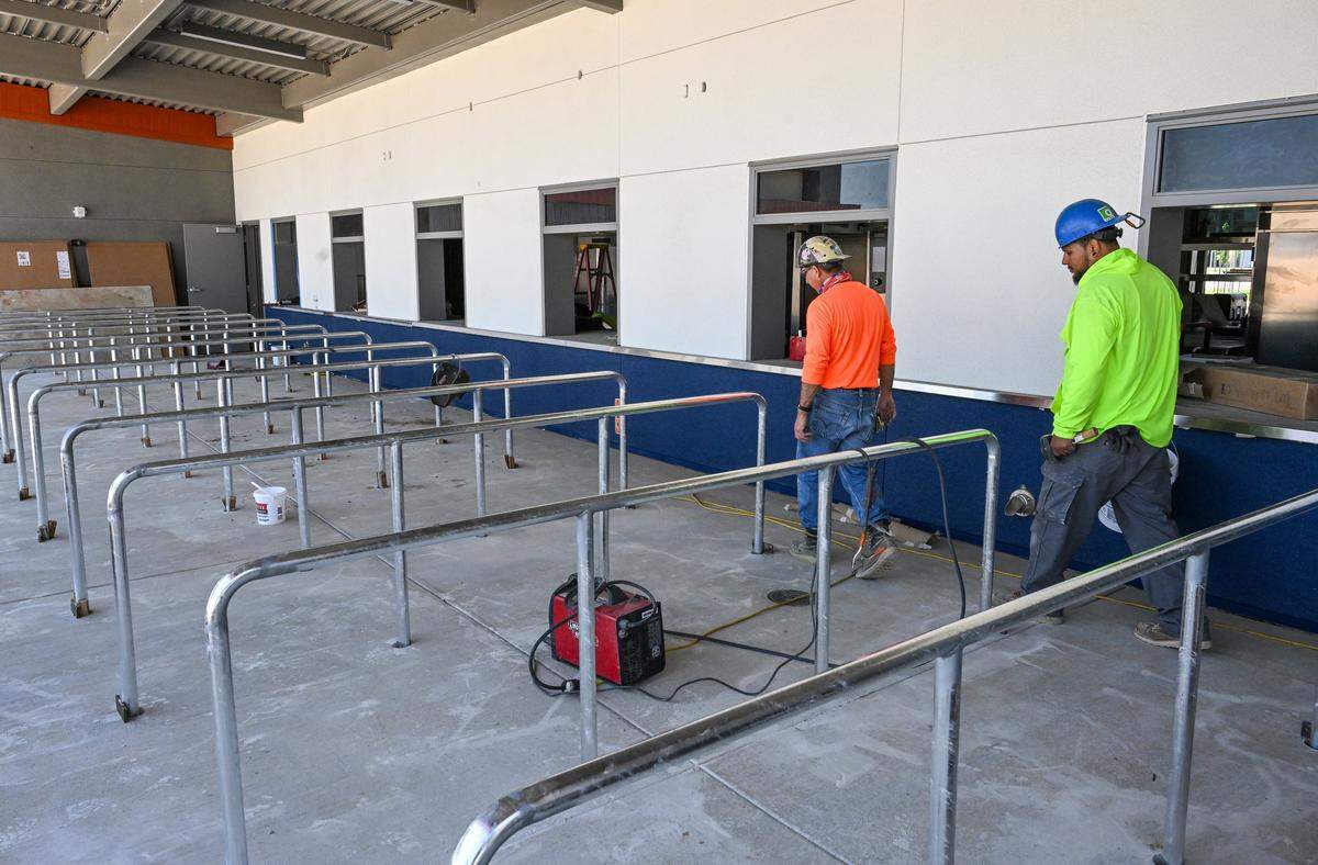 Construction workers walk by the new snack bar building at the Terry P. Bradley Educational Center, on Friday, Aug. 8, 2025 just days before the start of classes on August 18. 