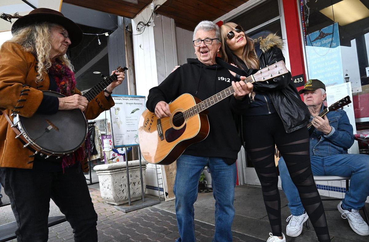 “Banjo Barbara” Larae Brown, left, accompanies Melvin Mason, known as Kuzzin Mel, center, with Victoria Roberts to the right outside Scoops, Soups & More on Pollasky Avenue in Old Town Clovis Thursday, Feb. 20, 2025.