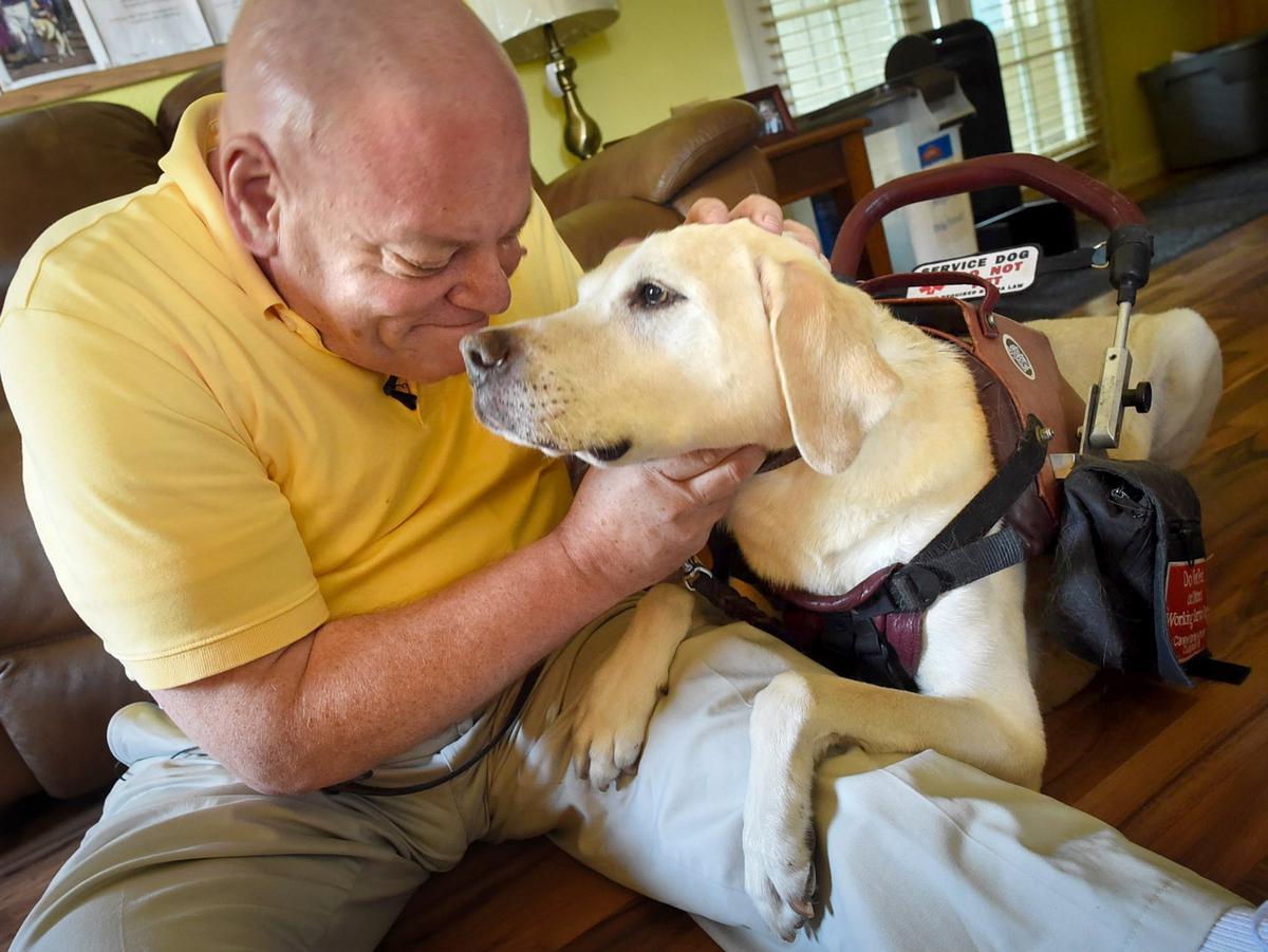 Edward Crane snuggles with his assistance dog Alepo in their Clovis home.