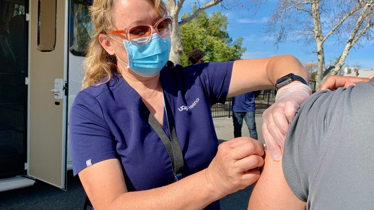Jolene Woods, RN, UCSF Fresno CEP, vaccinates a patient.