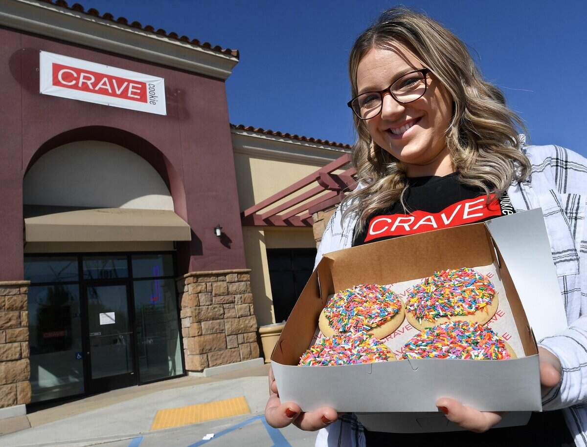 Shandi Scrivner, owner of Crave Cookie, holds a box of the popular sugar cookies at the opening of her first location, which features a drive-thru, at the Marketplace at El Paseo shopping center, April 15, 2021.