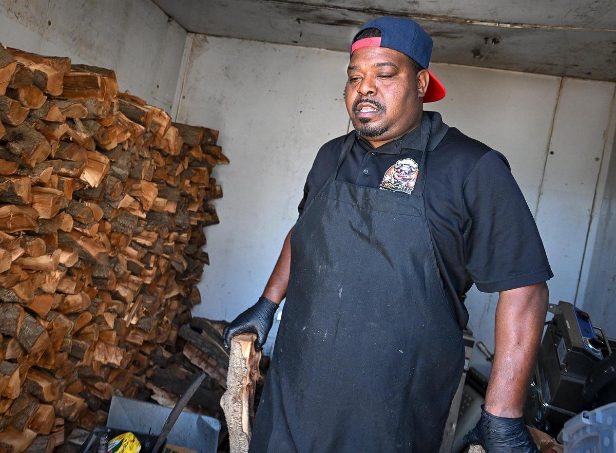 Herman Tatum, owner of Hogg Pitt BBQ & Catering, pulls almond wood logs from a storage container while grilling meats at his new brick-and-mortar restaurant in Fresno on Monday, June 2, 2025.