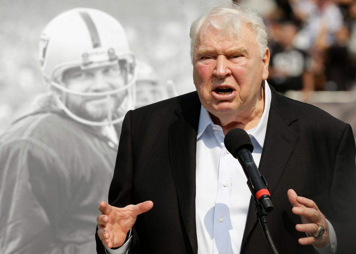 FILE - Former Oakland Raiders head coach John Madden speaks about former quarterback Ken Stabler, pictured at rear, at a ceremony honoring Stabler during halftime of an NFL football game between the Raiders and the Cincinnati Bengals in Oakland, Calif., Sept. 13, 2015. John Madden, the Hall of Fame coach turned broadcaster whose exuberant calls combined with simple explanations provided a weekly soundtrack to NFL games for three decades, died Tuesday, Dec. 28, 2021, the NFL said. He was 85.