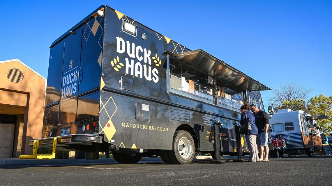 Hungry visitors look over the menu outside the new Duck Haus food truck at The Well Community Church in Fresno on Thursday, March 11, 2022.