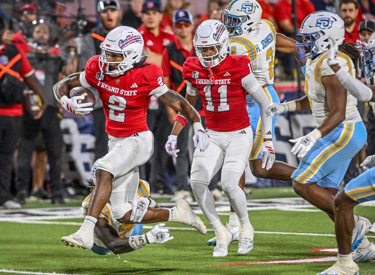 Fresno State's Rayshon Luke, left, jumps through the grasp of a Southern University player's grasp before getting into the end zone for a touchdown in the first half of their game at Valley Children's Stadium in Fresno on Saturday, Sept. 13, 2025. 