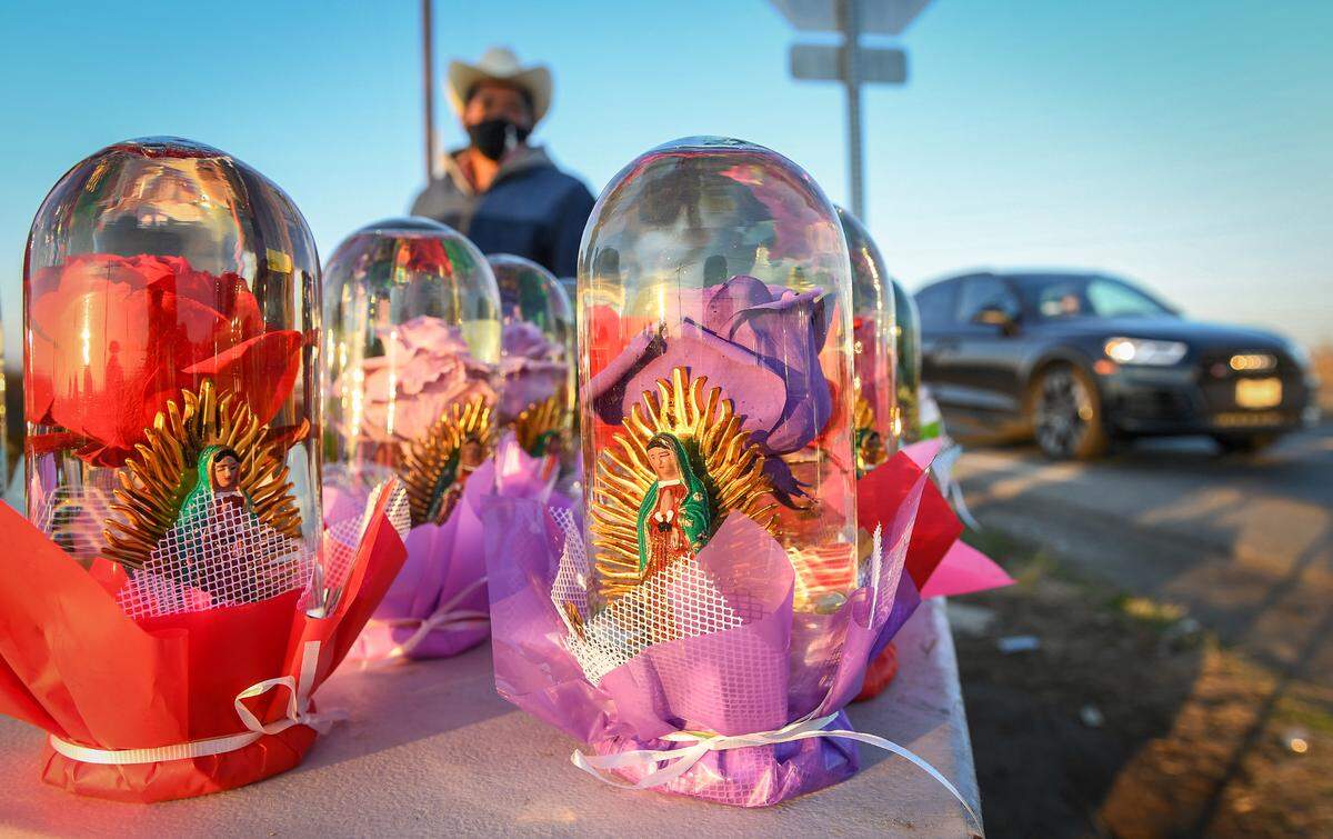Colorful roses with Virgin Mary idols sitting in water-filled glass displays are among the flower gifts Guillermo Lozano sells on the side of the road in rural Madera County, on Friday, Dec. 18, 2020.
