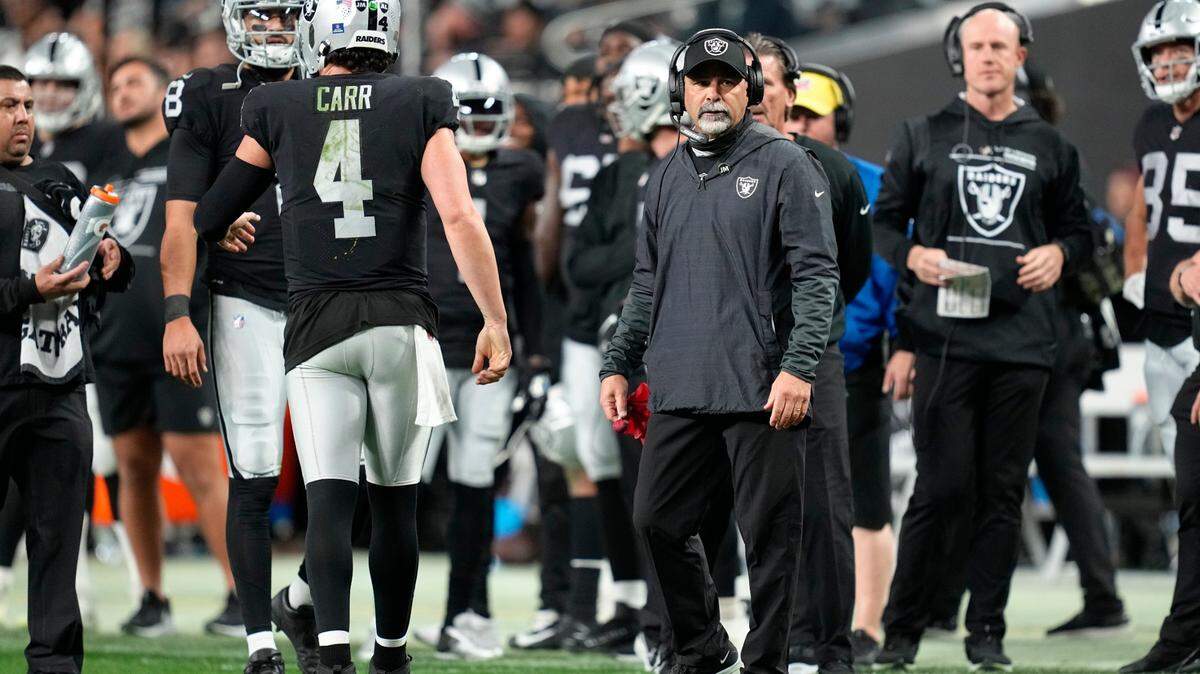 Rich Bisaccia talks with quarterback Derek Carr during a timeout during the second half of an NFL game against the Los Angeles Chargers, Sunday, Jan. 9, 2022, in Las Vegas.