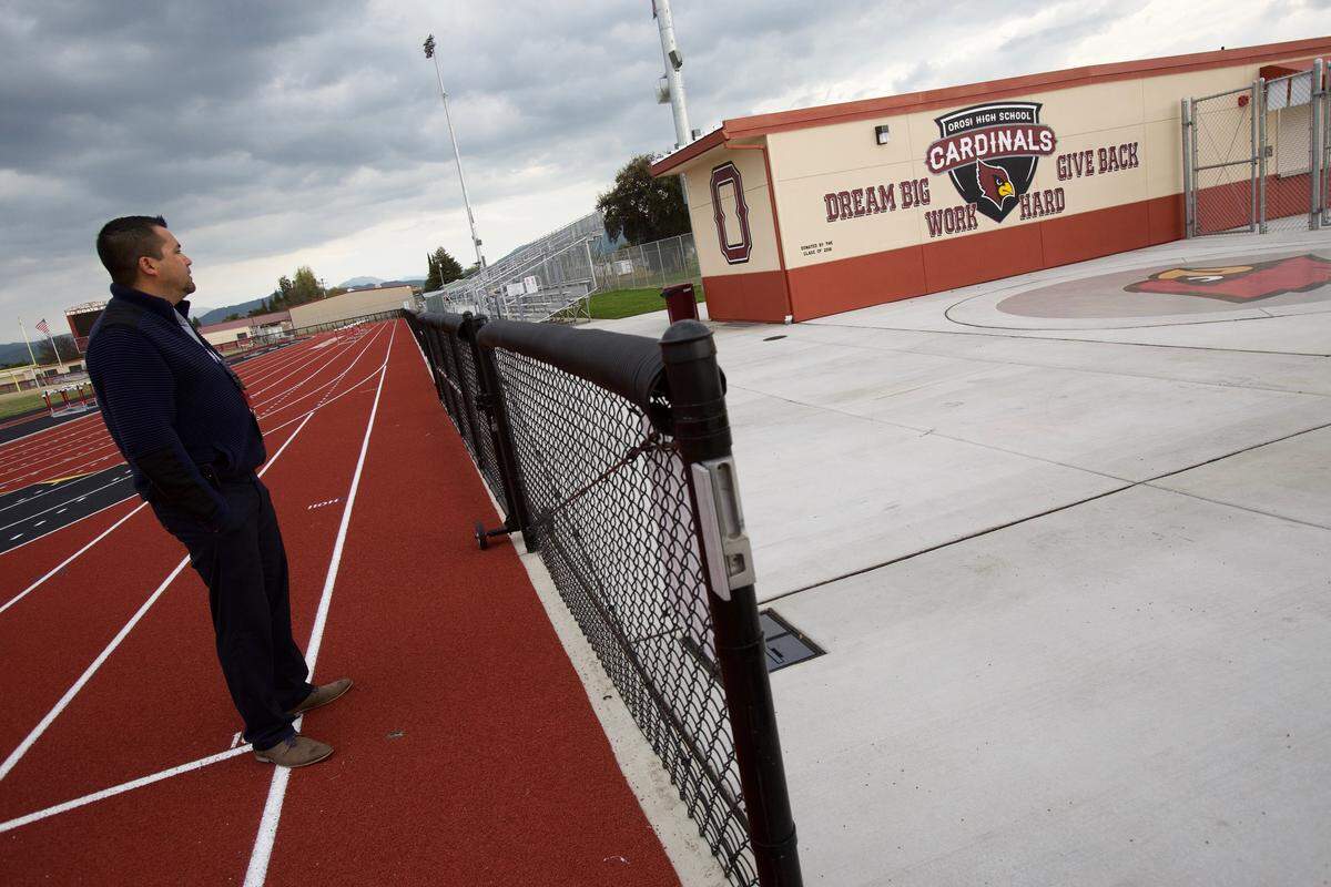 Orosi High principal Roberto Vaca points out a new mural visible from the new track and stadium at the school.
