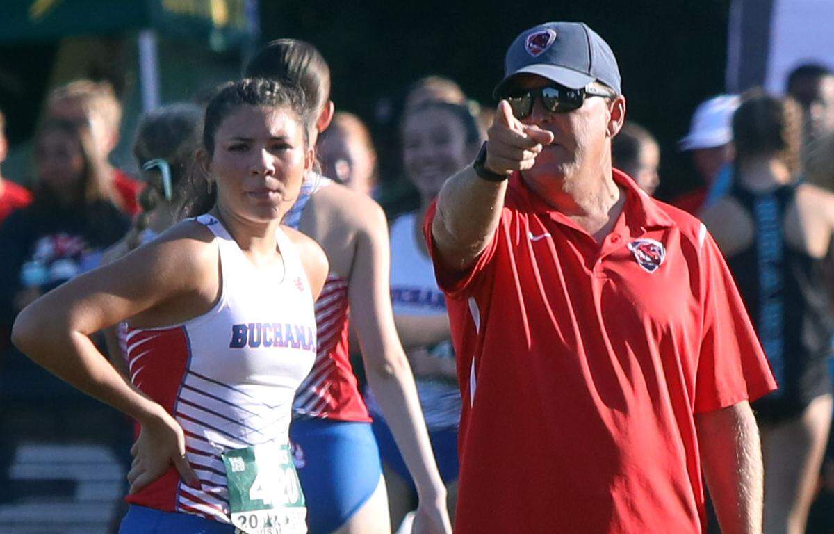 Buchanan High head coach Brian Weaver talks to junior Elle Lomelí before the Bill Buettner invitational flight of the 44th annual ASICS Clovis Invitational at Woodward Park on Oct. 7, 2023.