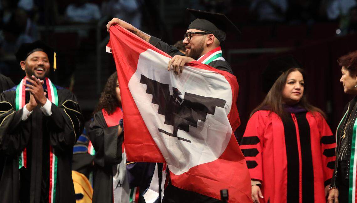 José Fernández, who earned a degree in business, unfurls the United Farm Workers flag during the 47th Chicano/Latino Commencement Celebration at the Save Mart Center on May 20, 2023.