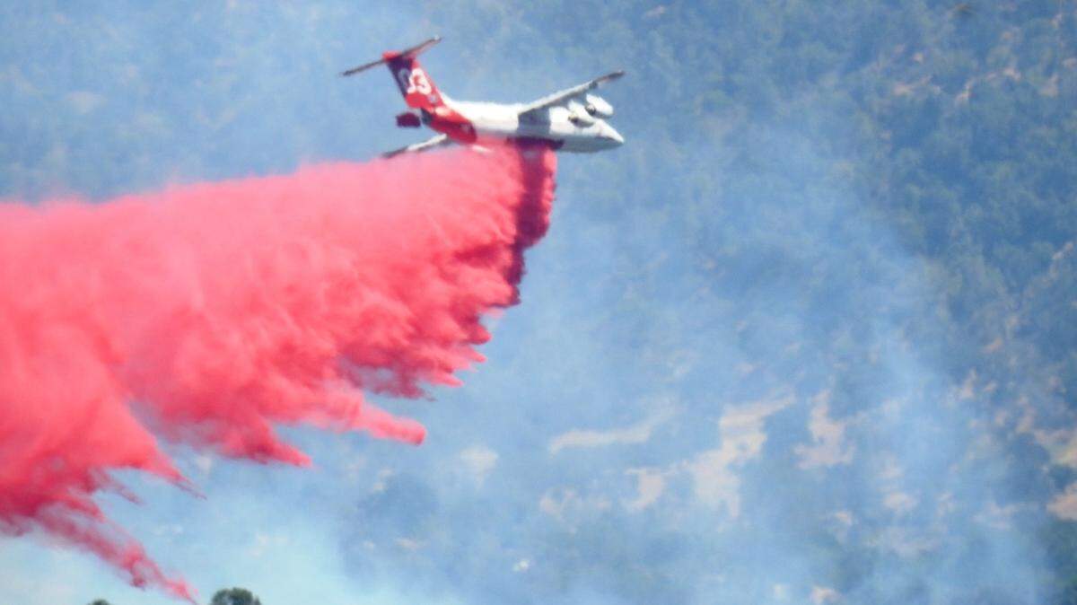 An aircraft bombs fast-moving flames near Cascadel Woods with fire retardant Monday afternoon. The Madera County Sheriff ordered evacuations for the area.