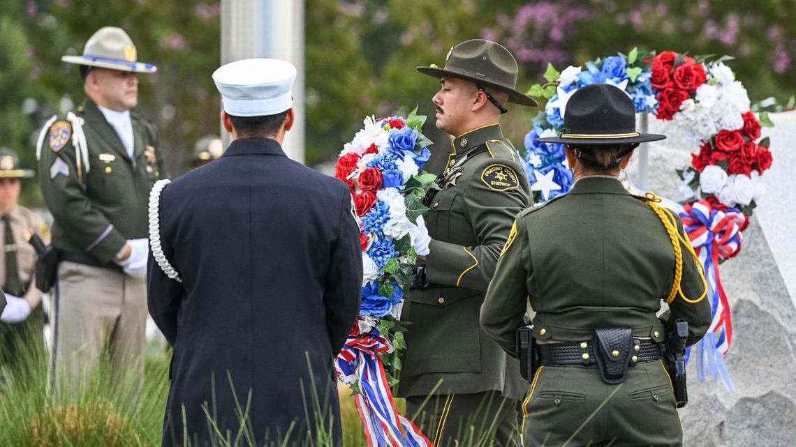 A Fresno County sheriff’s deputy carries in one of five wreaths laid out to represent New York police officers, firefighters, port authority members, military and civilians lost in the World Trade Center attack on September 11, 2001, during the 21st anniversary September 11 Memorial Ceremony at the California 9/11 Memorial in Clovis on Sunday, Sept. 11, 2022.