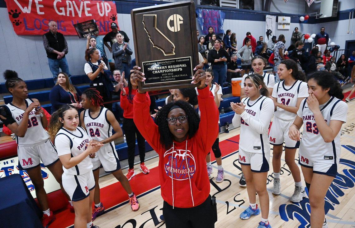 San Joaquin Memorial’s head coach Verenique Warren, center, holds up the winning plaque after defeating Antelope 50-38 in CIF regional final basketball action Tuesday, March 8, 2022 in Fresno.