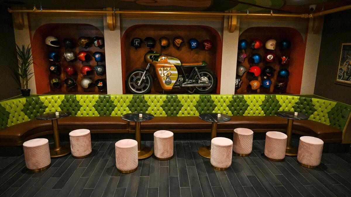 A large seating area at The Howlin Wolf cocktail bar in the Tower District Fresno features seating repurposed from the closed Chicken Pie Shop, and a motorcycle on display surrounded by numerous helmets. Photographed on Tuesday, Dec. 14, 2021.