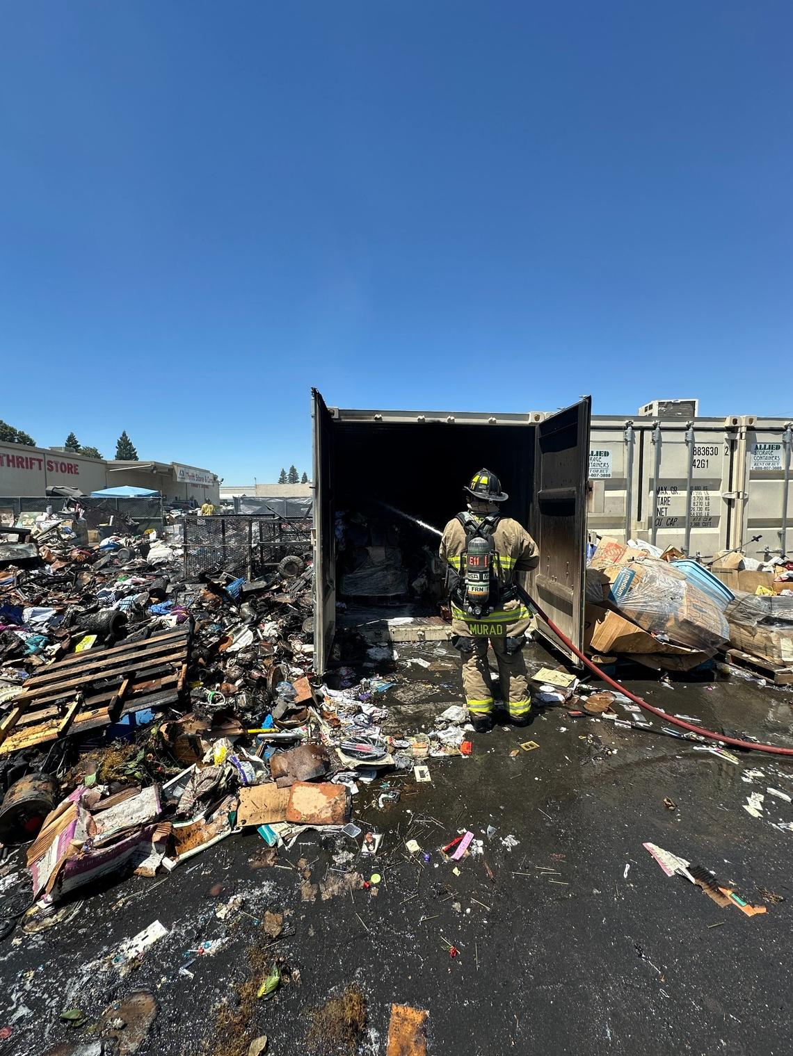 A Fresno firefighter uses a hose to water down a pile of burnt donations on Thursday, July 10, 2025.