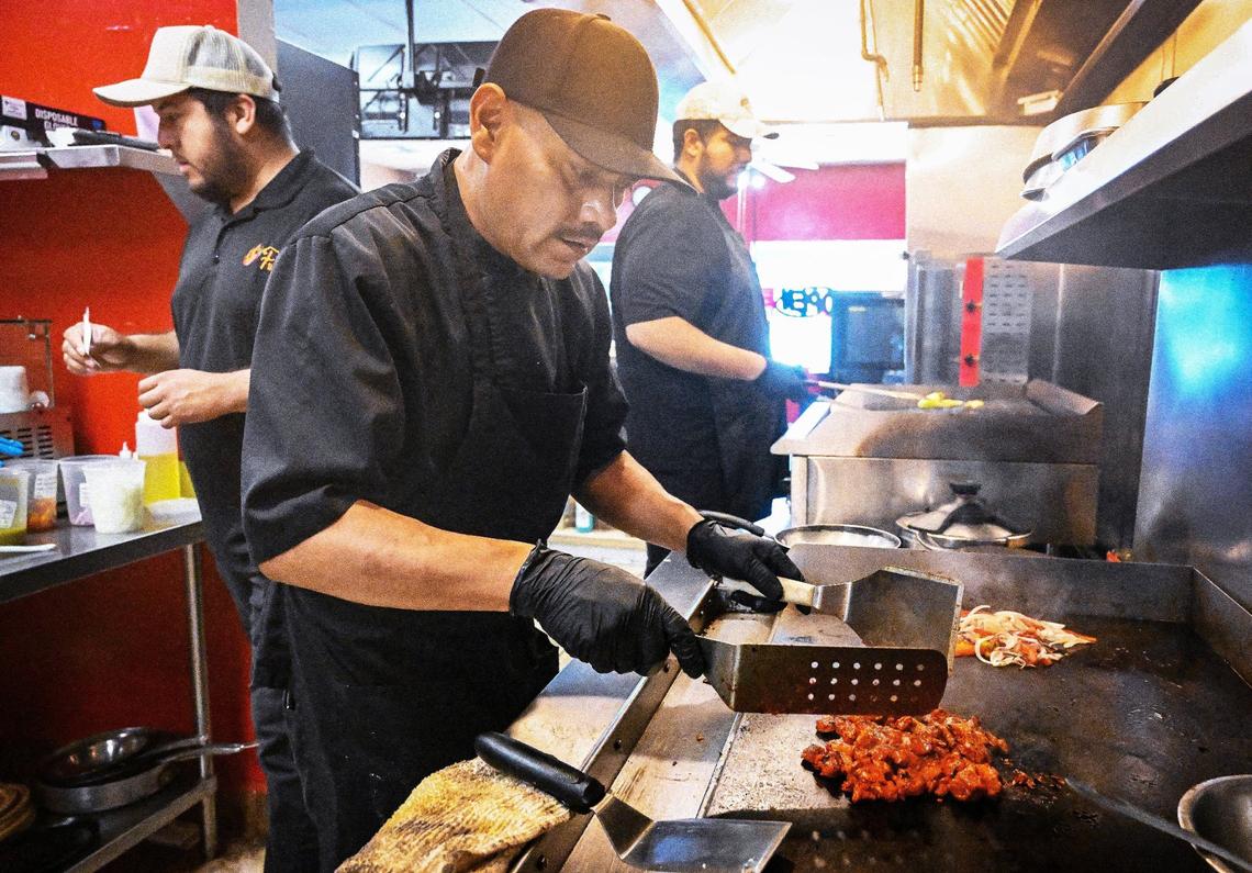 Fuego Taqueria y Restaurante cook Armando Juarez sears pastor meat on the griddle while restaurant co-owners Aldo Ramirez and his brother Anton Ramirez work on orders on Thursday, Aug. 22, 2024.