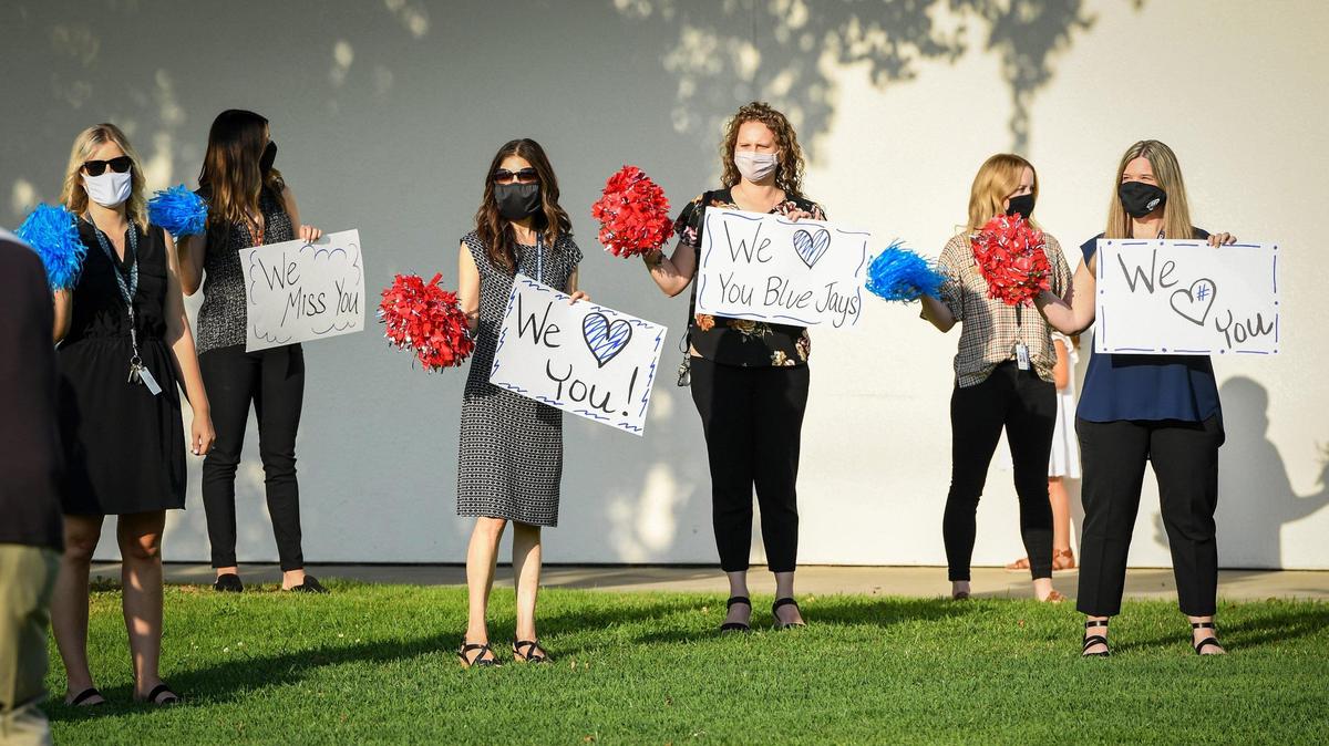 Jefferson Elementary School teachers stand socially distanced with masks on the grass in front of the school in Clovis before the start of their annual bell ringing tradition to signify the start of the school year on Monday, Aug. 17, 2020.
