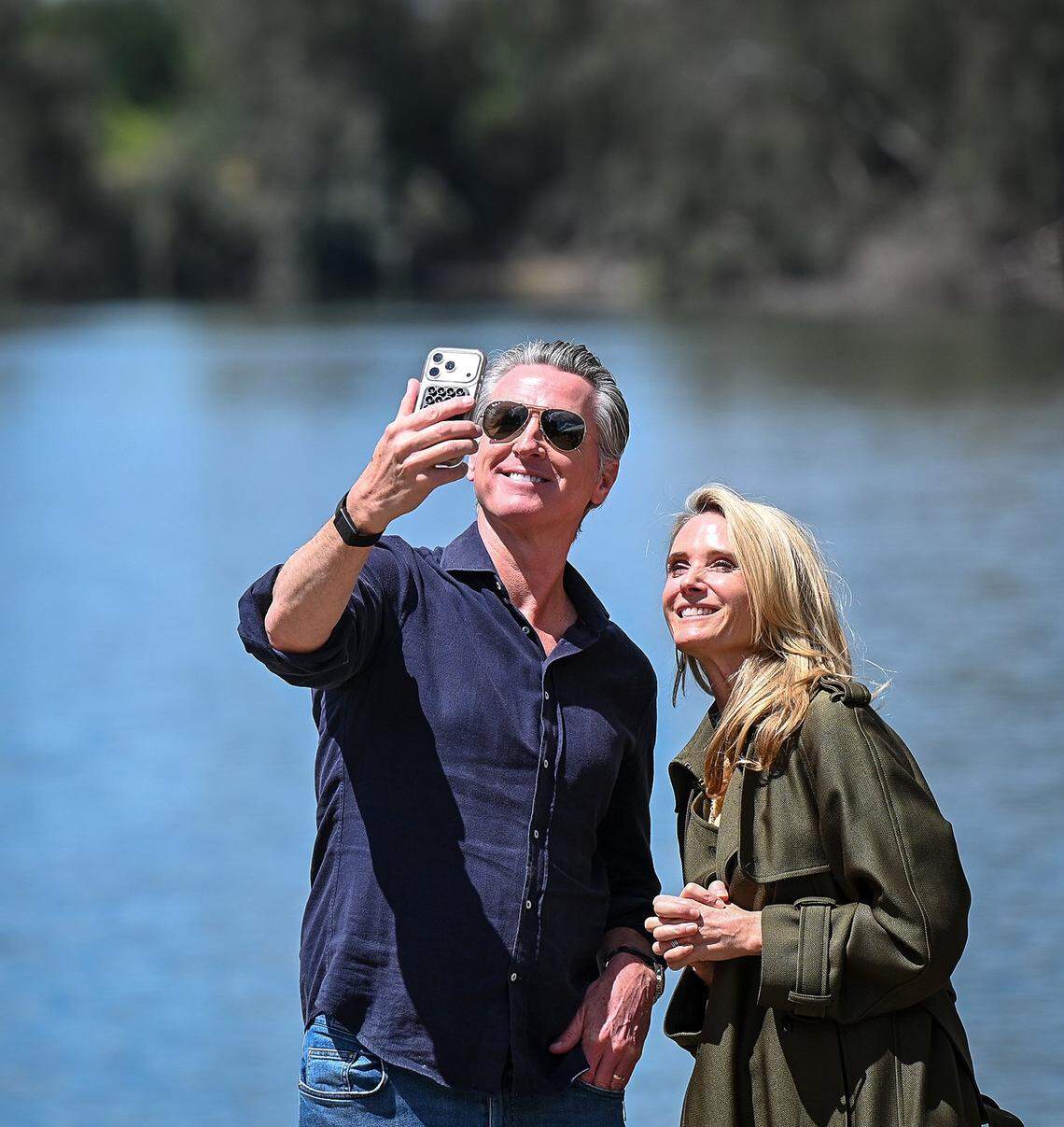 California Gov. Gavin Newsom and his wife, first partner Jennifer Siebel Newsom, hold a FaceTime call after announcing the expansion of the state park system during a news conference near the Sycamore Island fishing dock along the San Joaquin River Parkway in Madera County on Wednesday, April 22, 2026.