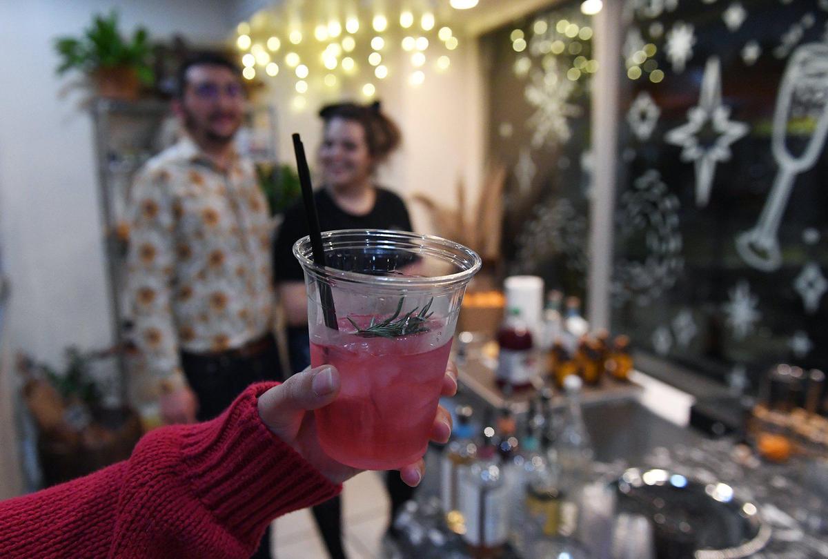 Princess Kosinski of the Wildflower Collective holds forth the mockatil The Lamplighter, made by Ian Landis of Bone Dry Sober Bar, background left, at a popup during Art Hop Thursday, Dec. 2, 2021 in Fresno.