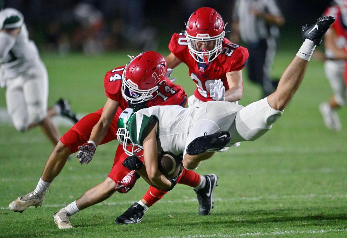 Sanger’s Nathan Pena, left, stops Dinuba’s Noah Gonzalez, right, on a punt return Friday, Aug. 18, 2023 in Sanger.