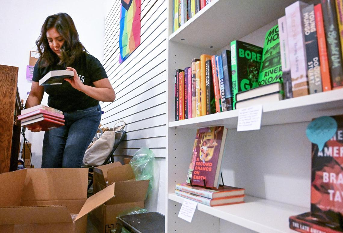 Ashley Mireles-Guerrero opens of newly arrived books at her indie bookstore, Judging by the Cover, which recently opened in Fresno’s Chinatown.