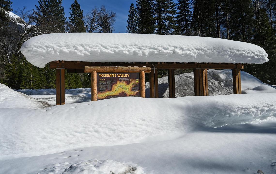 A Yosemite Valley bus stop is covered in snow with banks piled high making many areas inaccessible.