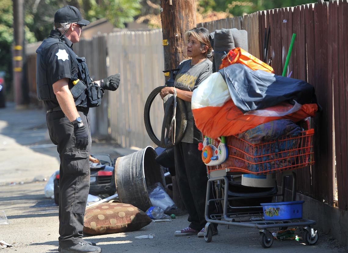 Officer Gary Holden advises Elena Zurala of help she can receive after she was told she was in violation of Fresno’s no-camping ordinance during a cleanup of an alley in 2018. 
