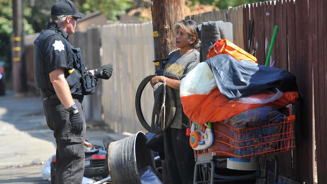 Officer Gary Holden advises Elena Zurala of help she can receive after she was told she was in violation of Fresno’s no-camping ordinance during a cleanup of an alley in 2018.