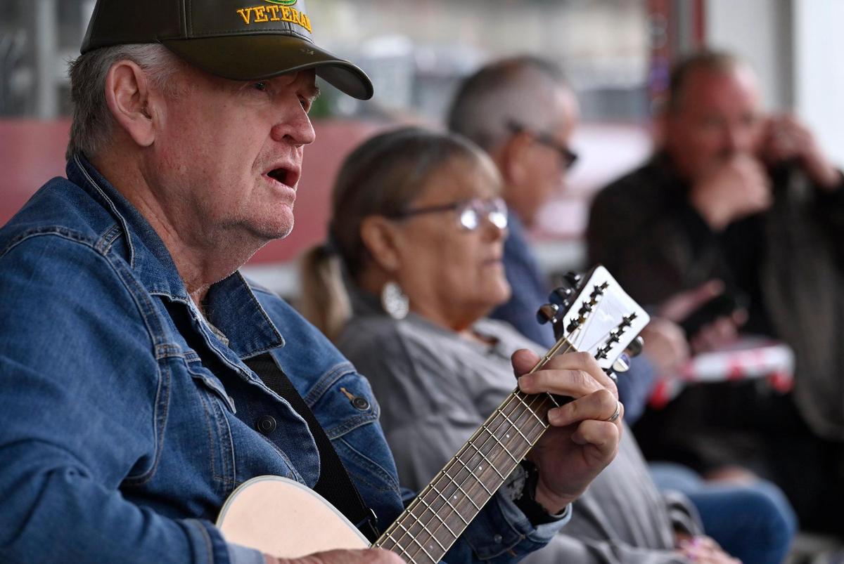 Bob Satterwhite, left, takes his turn urged by Melvin Mason, known as Kuzzin Mel, playing to a group gathered outside Scoops, Soups & More on Pollasky Avenue in Old Town Clovis Thursday, Feb. 20, 2025.