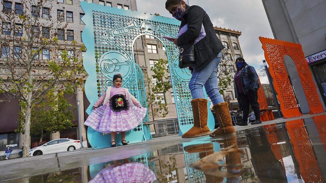 Maria Velasco, right, steps over water after photographing her granddaughter, Victoria Orozco, 6, in her new ballet folklorico costume for Teocalli Cultural Academy Saturday afternoon following a rainy morning Jan. 23, 2021 in Fresno.